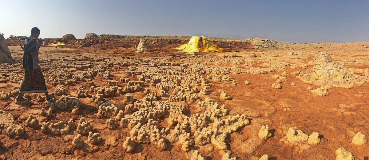 Lagunas desecadas con restos ferruginosos, y al fondo una montaña de azufre amarillo